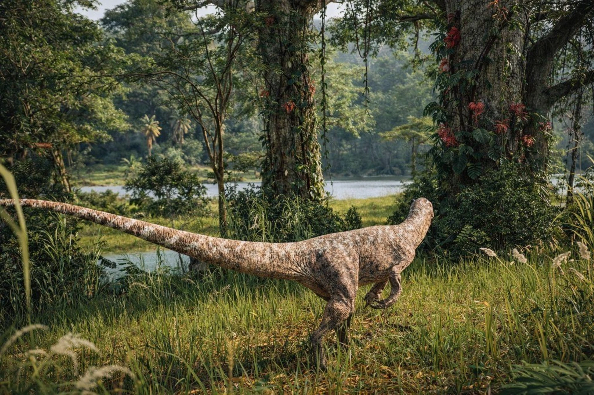 A bipedal dinosaur in tall grass beside a jungle lake, with vine-covered trees and red flowers.